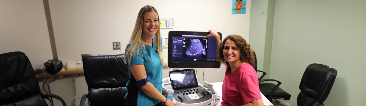 Two nurses examine an image on a computer, collaborating on patient care and sharing insights